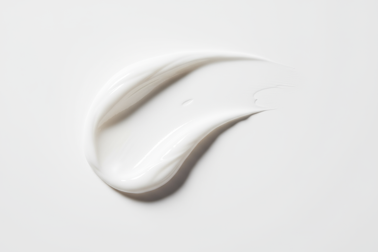 a white cream swipe against a white backdrop in a studio setting with diffused light and shadow