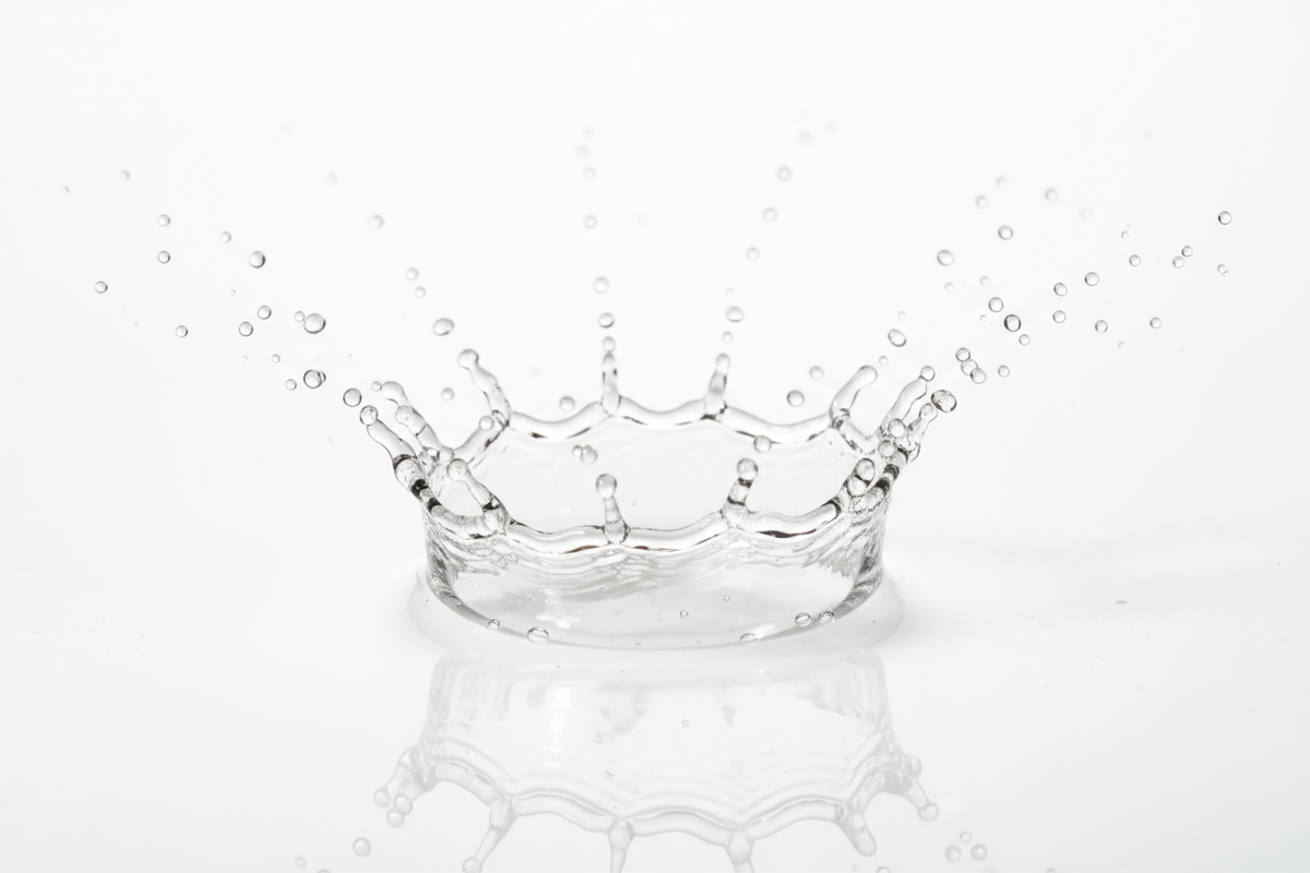 clear drops of toner splashing against a white surface. 90mm focal. close up. medical grade skincare aesthetic